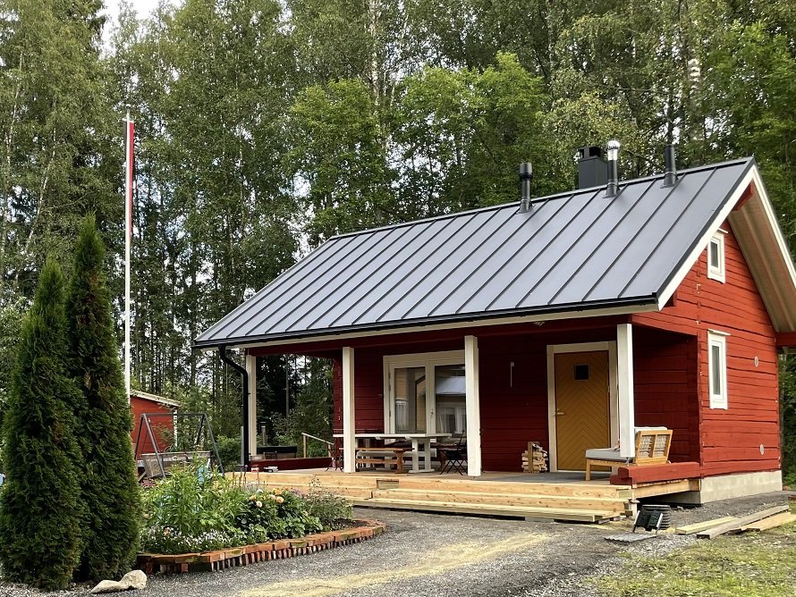 Valmis punainen hirsirakennus kuisteineen ja konesaumattuine kattoineen kesällä