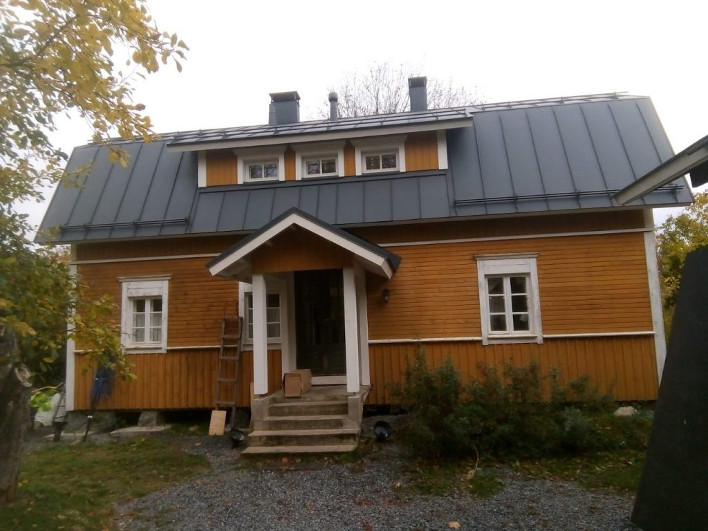 Sama keltainen puutalo perusparannuksen jälkeen, uusi konesaumattu katto ja kattolyhty