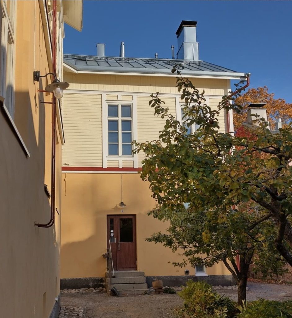 Kerrostalon sisäpiha perusparannuksen jälkeen, kalkkimaalattu rappaus ja vaalea puuverhous